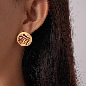 Close-up of vintage golden round textured earrings worn on ear showing detailed ridges