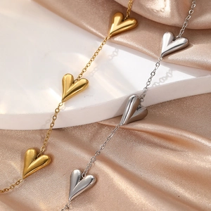 Close-up of polished gold and silver heart pendants on satin fabric background