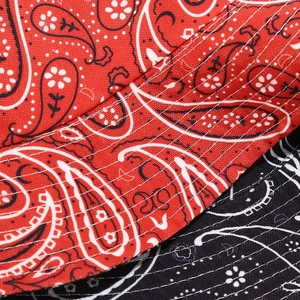 Gros plan d'un bob réversible rouge et noir avec motifs paisley et surpiqûres blanches