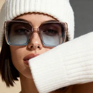 Close-up of oversized square sunglasses with gradient blue lenses and champagne frame