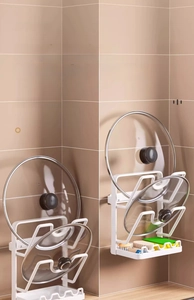 Close-up of wall-mounted white lid rack holding lids and cleaning sponges in a kitchen