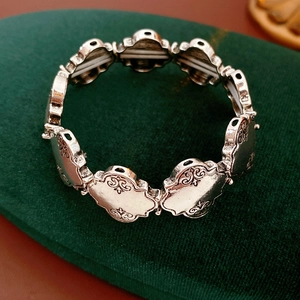 Gros plan de maillons de bracelet argenté vintage avec gravures sur velours vert
