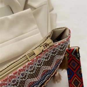 Detail of ethnic geometric woven pattern bag with gold zipper and tassel accessory