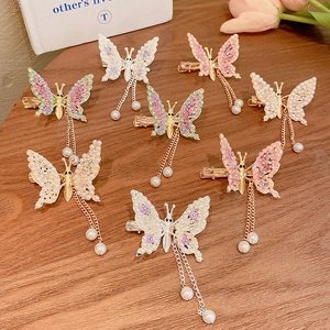 Detail of butterfly hair clips with gold tassels and pearls on a warm wooden surface