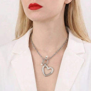 Gros plan du pendentif cœur argenté avec strass et perles sur le cou d'une femme