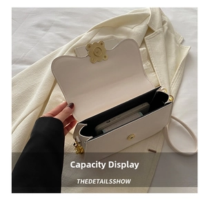 Detail shot showing internal capacity of the off-white crossbody bag with a smartphone