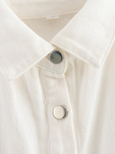 Detail of white twill cotton fabric with circular silver metal buttons and stitching