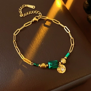 Détail du bracelet chaîne doré vintage avec pierres vertes et breloque ronde en zircon