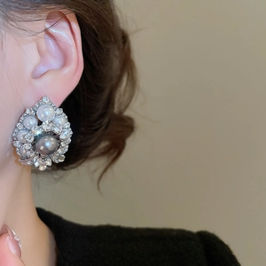 Close-up of model wearing retro teardrop earrings with gray pearls and crystals