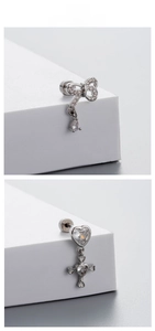 Detailed view of silver bow and heart cross earrings with sparkling zircon stones