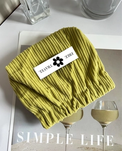 Detailed close-up of a yellow corduroy cosmetic pouch with Free Travel label on a magazine