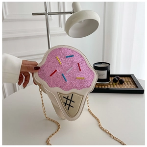 Detail of ice cream cone bag with pink glitter top and gold chain on a white table