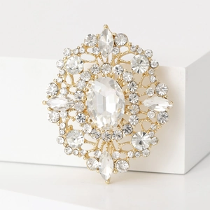 Macro detail of vintage gold brooch with sparkling oval rhinestones and filigree patterns