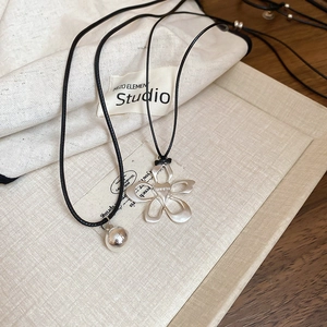 Detail of silver hollow flower and bead pendants on black cord necklaces with premium finish