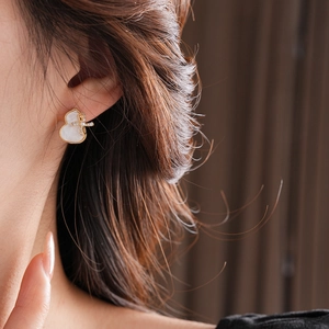 Detail of gold gourd stud earring featuring white shell inlay and side zircon accents