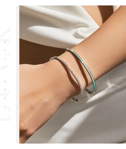 Detail of stacked silver bracelets with pavé diamonds and turquoise enamel accents