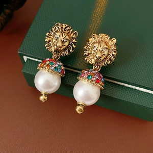 Dettaglio degli orecchini vintage a testa di leone con strass colorati e grandi perle
