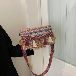 Detail of bohemian woven crossbody bag with colorful tassels and gold chain accent