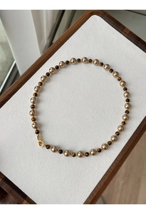 Détail des perles plaquées or et des pierres oeil de tigre sur un collier vintage