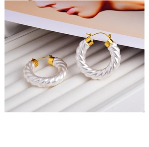 Detail of French vintage style white spiral hoop earrings with elegant gold metal clasp