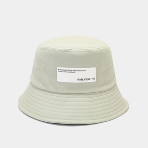 Detailed macro view of the cotton twill fabric and white logo patch on the green bucket hat