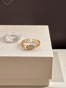 Detail of silver and gold fish-shaped open rings with shimmering micro-set zircons