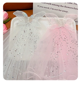 Detailed view of white and pink glittery bow veils with pearls and tulle texture