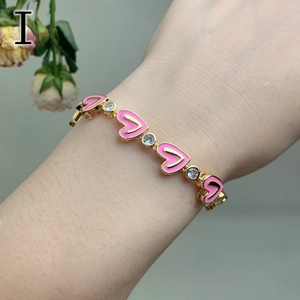 Detail of gold heart bracelet with pink enamel inlay and sparkling zircon stones