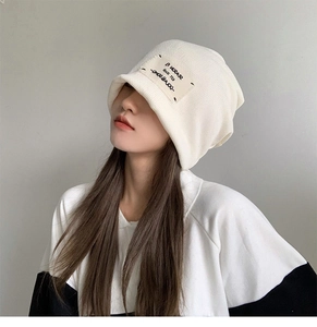 Detail view of a white knitted bucket hat with a small patch label on the side