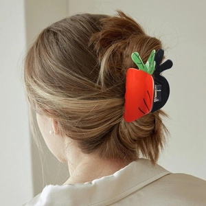 Detailed view of a creative carrot shaped hair claw clip in vibrant orange and green