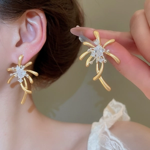 Detail view of gold abstract floral earrings with cubic zirconia worn on ear