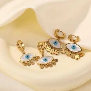 Detail of four golden stainless steel evil eye earrings with shell inlay and fringe tassels