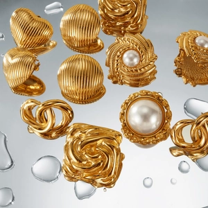 Detailed view of vintage gold plated earrings with pearls on a reflective water surface