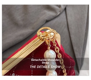 Detail view of red velvet shell bag featuring gold metal frame and pearl chain strap