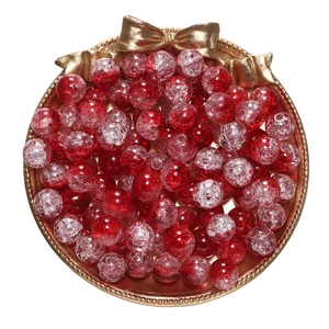 Macro shot of red and clear crackle glass beads for DIY jewelry in a gold tray