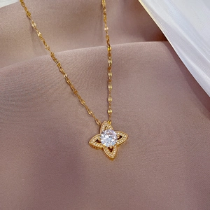 Detailed close-up of a gold clover pendant with sparkling zircon on ripple chain