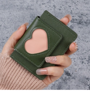 Close-up of a hand holding a green litchi leather mini wallet with a pink heart window