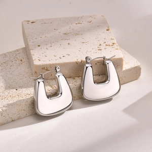 Macro shot of silver U-shaped earrings with polished finish on a textured stone base