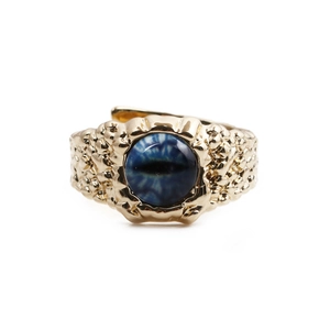 Detail of gold hammer-textured ring featuring a blue eye-shaped gemstone centerpiece