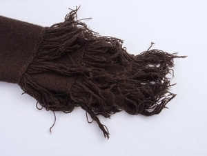 Detail of dark brown knit cardigan showing textured fringe tassels and woven hem finish