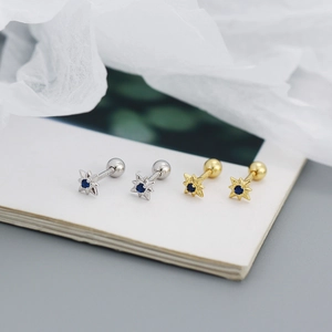 Macro detail of gold and silver eight-point star stud earrings with blue zircon