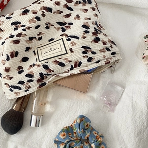 Detailed macro view of leopard print pleated makeup bag with zipper and cosmetic props