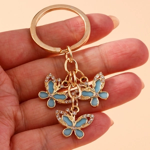 Close-up of golden butterfly keychain with blue enamel wings and sparkling rhinestones