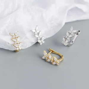 Detailed view of gold and silver leaf-shaped U-shaped earrings with inlaid crystals