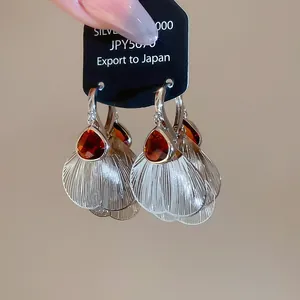 Detail view of silver earring featuring a tea-colored pear stone and frosted fan petal charm