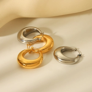 Polished stainless steel hollow hoop earrings in gold and silver finish on beige background