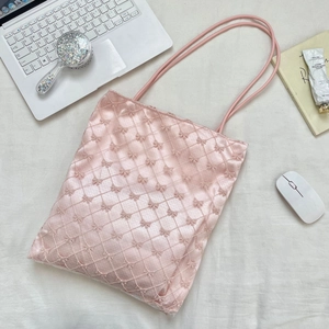 Vue détaillée du sac cabas rose avec nœuds en dentelle, matelassage et accessoires quotidiens