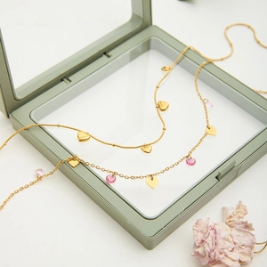 Close-up of golden layered heart necklace with pink crystals in a PE film jewelry box