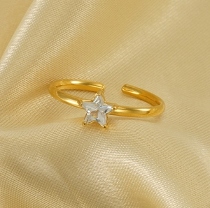 Macro detail of gold star ring with zircon stone on elegant silk fabric background