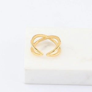 Detail of gold double-layer cross ring with rainbow cubic zirconia on marble stand